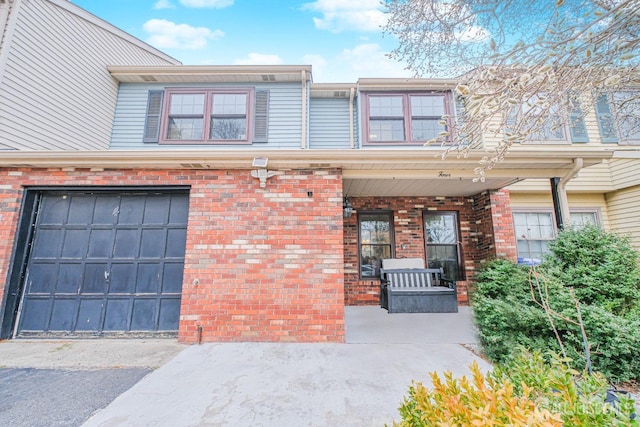 view of front of house with covered porch, brick siding, and an attached garage