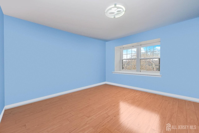 spare room with baseboards and wood finished floors