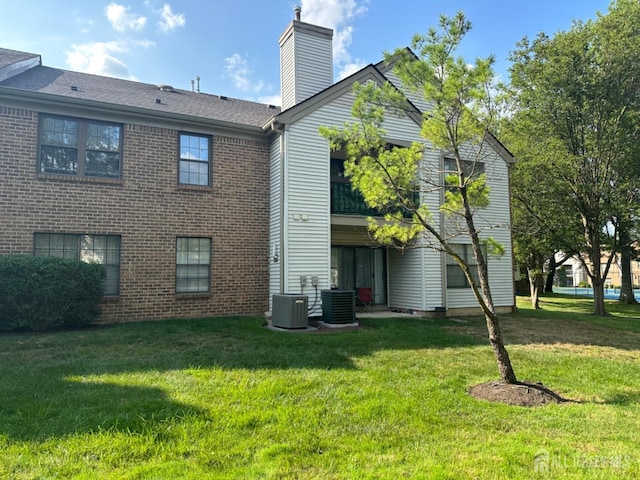 1202 Harbor Club Dr, Sayreville, NJ 08859 - back of property featuring brick siding, central AC unit, a yard, and a chimney