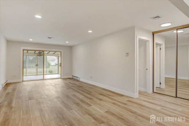 spare room featuring light wood-type flooring, a baseboard radiator, visible vents, and recessed lighting