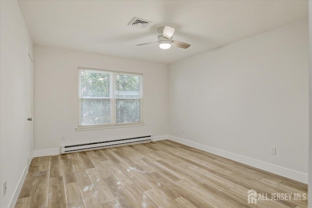 spare room featuring a baseboard heating unit, light wood-style flooring, and baseboards