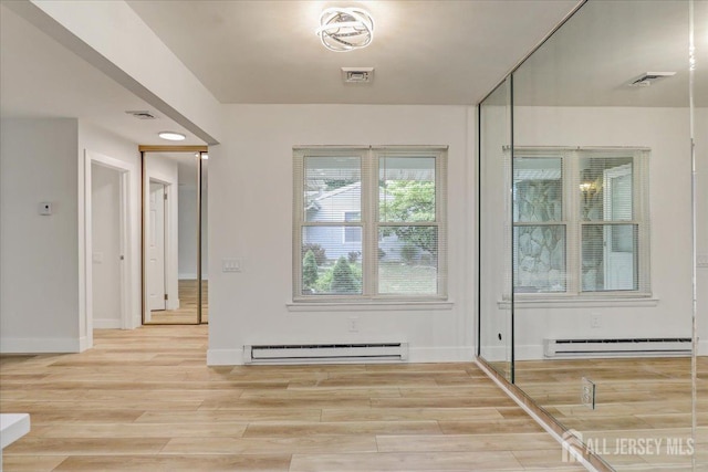 doorway to outside featuring visible vents, baseboard heating, and wood finished floors