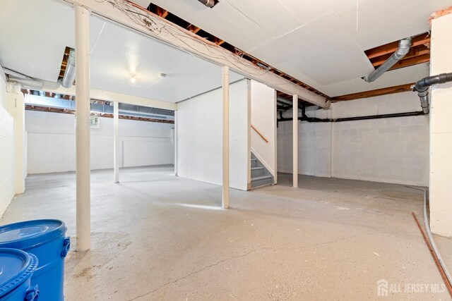 unfinished below grade area with concrete block wall and stairs