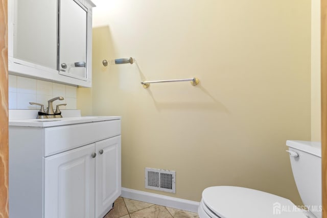 bathroom featuring vanity, toilet, baseboards, backsplash, and visible vents