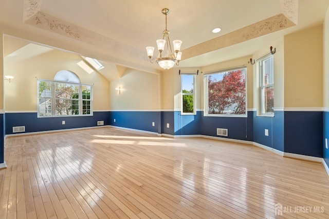empty room with a healthy amount of sunlight, an inviting chandelier, and visible vents