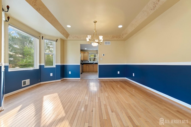 unfurnished room with a chandelier, baseboards, visible vents, and light wood-style floors