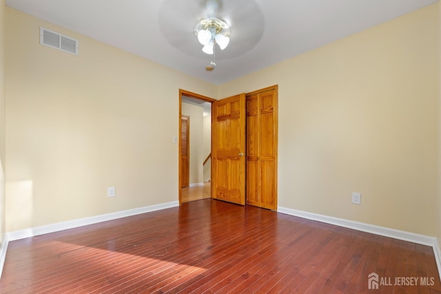 unfurnished bedroom with a ceiling fan, baseboards, dark wood-type flooring, visible vents, and a closet