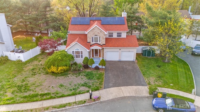 view of front of property with fence, solar panels, a front lawn, and aphalt driveway