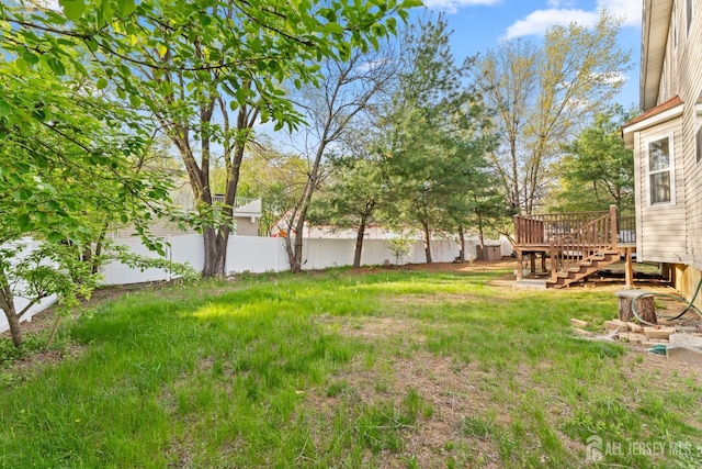 view of yard with fence, a wooden deck, and stairs