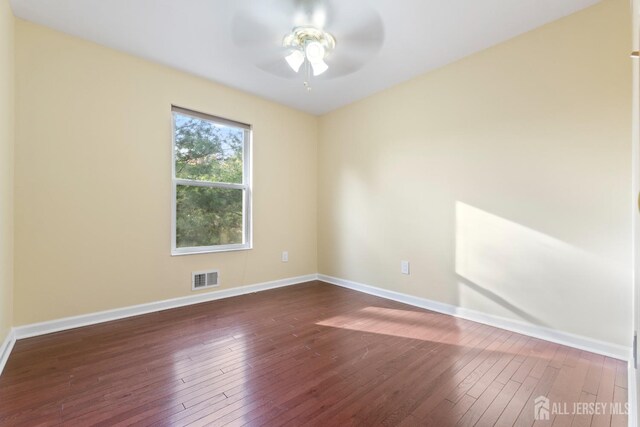 empty room featuring visible vents, dark wood finished floors, ceiling fan, and baseboards