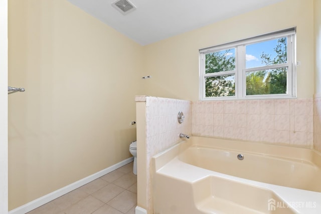 full bath featuring toilet, tile patterned floors, baseboards, visible vents, and a garden tub