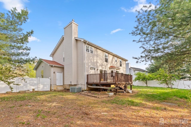rear view of house featuring central AC unit, a wooden deck, a chimney, and fence
