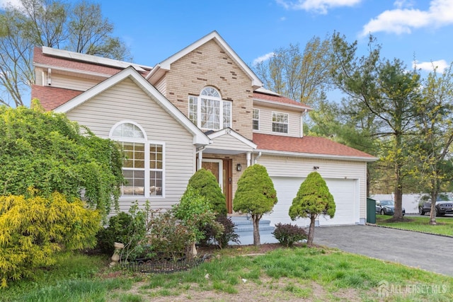 traditional-style house with a shingled roof and aphalt driveway