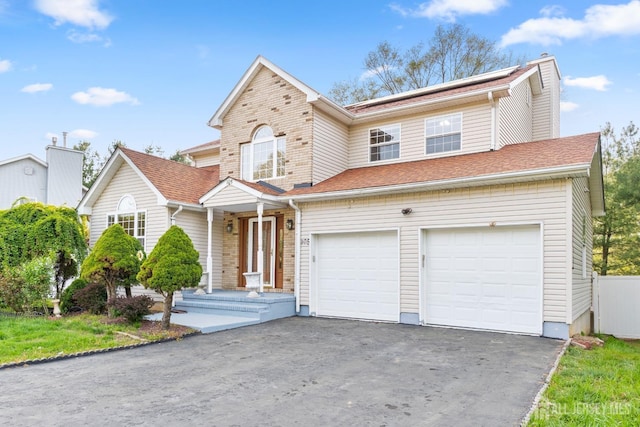 traditional-style home featuring an attached garage and aphalt driveway
