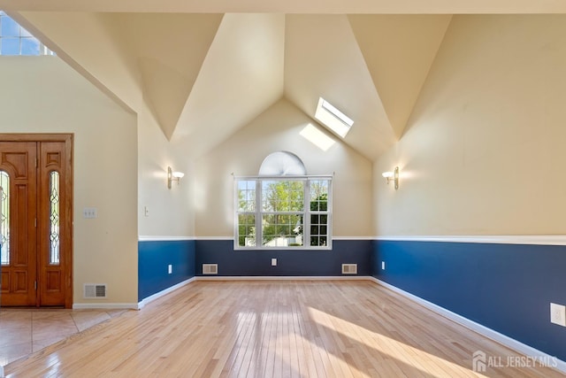 interior space with a skylight, hardwood / wood-style floors, and visible vents