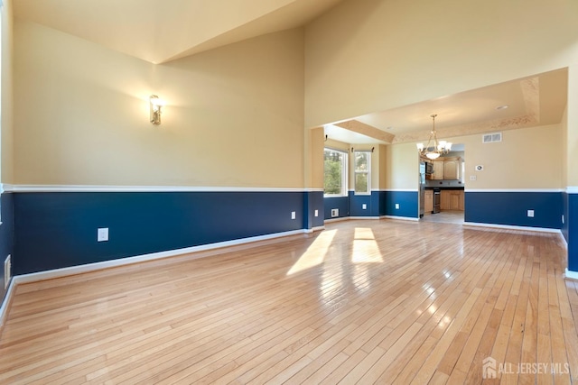 interior space with baseboards, a chandelier, visible vents, and light wood-style floors
