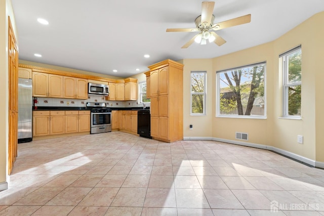 kitchen featuring visible vents, light brown cabinetry, dark countertops, baseboards, and appliances with stainless steel finishes