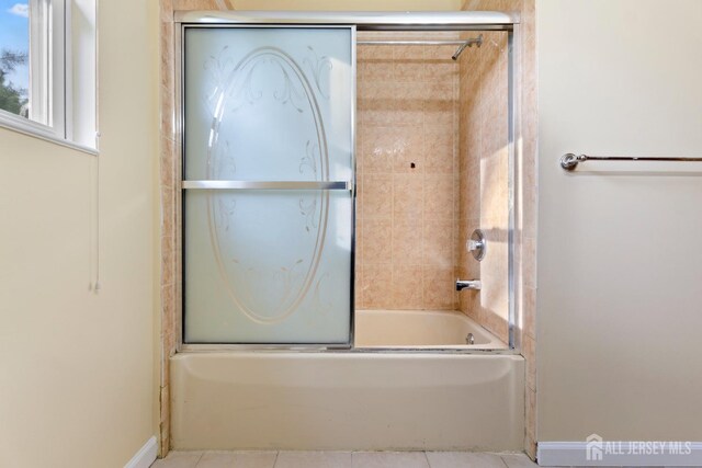 bathroom with baseboards, tile patterned flooring, and bath / shower combo with glass door