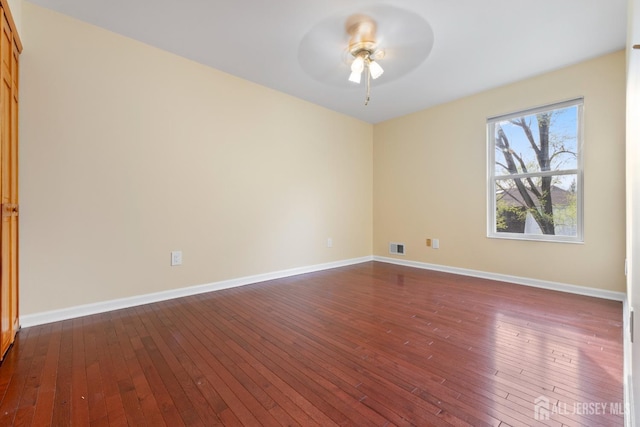 spare room with ceiling fan, visible vents, dark wood-style floors, and baseboards
