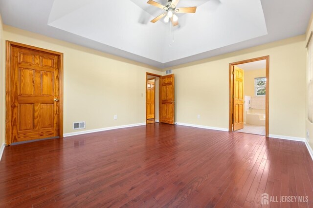 unfurnished bedroom with connected bathroom, baseboards, visible vents, and dark wood-style floors
