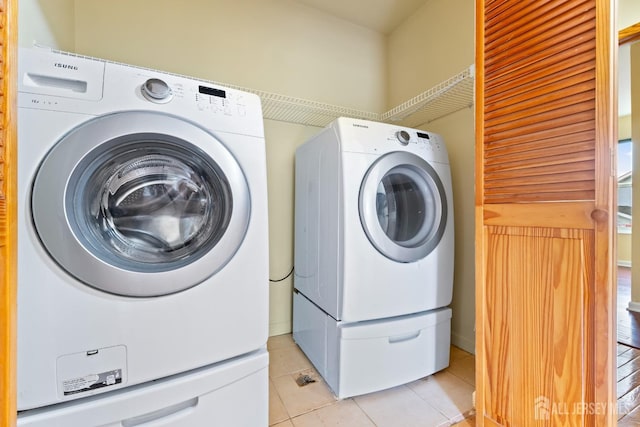 clothes washing area featuring separate washer and dryer, laundry area, and light tile patterned flooring