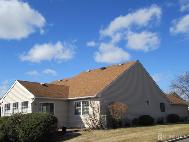 view of home's exterior featuring roof with shingles and a yard