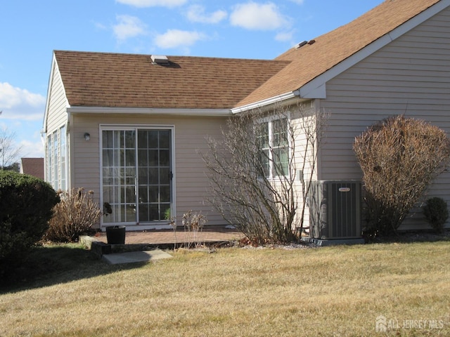 view of home's exterior with a yard, roof with shingles, and central air condition unit