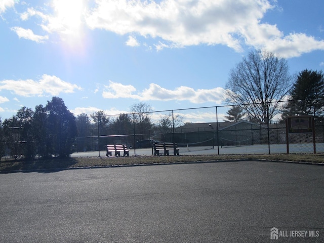 exterior space featuring a tennis court and fence