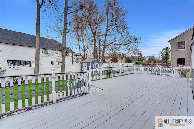 wooden terrace featuring a shed, an outdoor structure, and fence