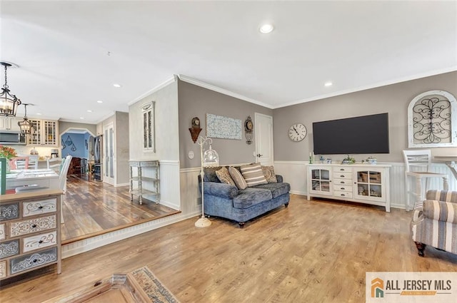 living room featuring ornamental molding, wood finished floors, a wainscoted wall, recessed lighting, and a chandelier