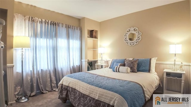 bedroom with carpet flooring and a wainscoted wall