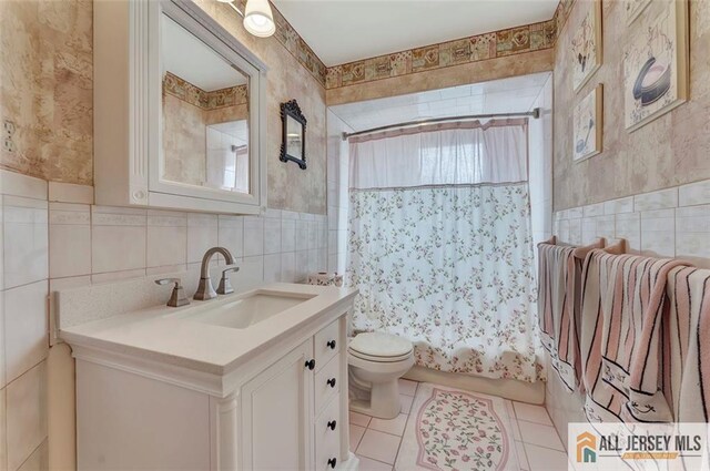 full bathroom with tile walls, toilet, tile patterned floors, shower / bath combo, and vanity