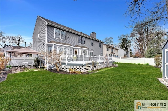 rear view of property with a gazebo, a wooden deck, a chimney, and a patio