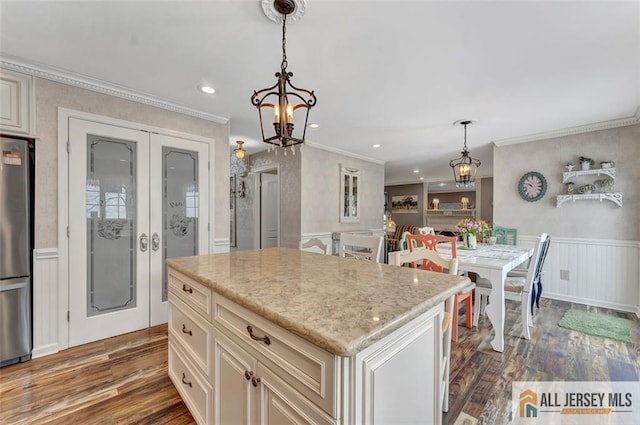 kitchen with a chandelier, freestanding refrigerator, wood finished floors, crown molding, and wainscoting