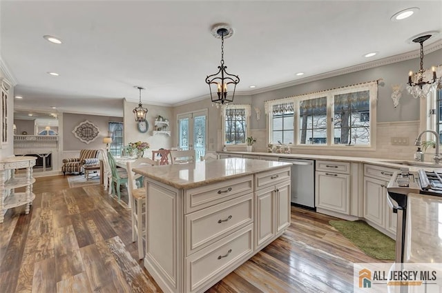 kitchen with stainless steel appliances, a sink, a chandelier, light stone countertops, and wood finished floors
