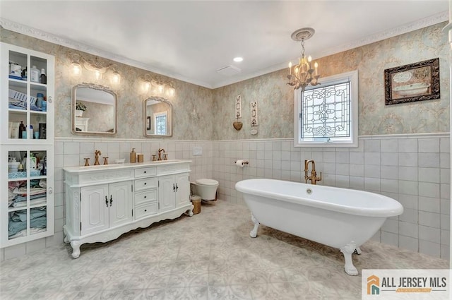 full bath featuring a soaking tub, double vanity, tile walls, a chandelier, and wainscoting