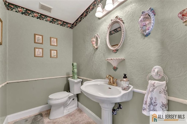bathroom featuring toilet, tile patterned flooring, and baseboards