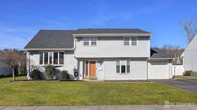 split level home with central AC, a garage, and a front lawn