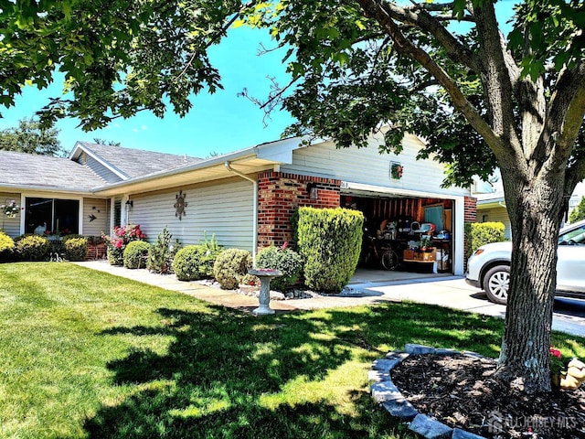 view of side of property with a garage, brick siding, a yard, and driveway