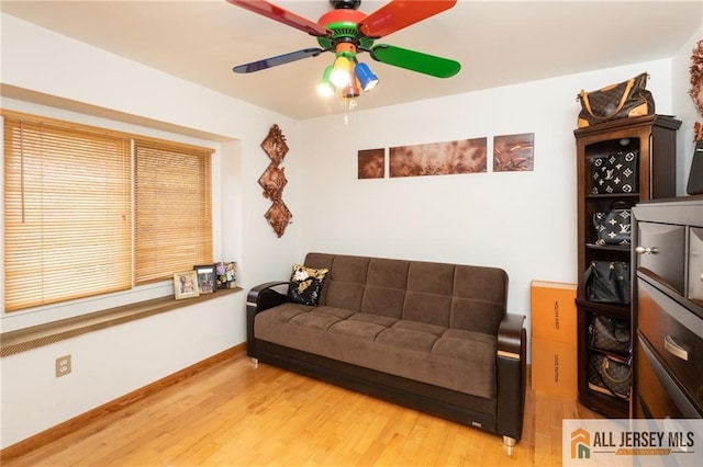 living room with baseboards, ceiling fan, and wood finished floors