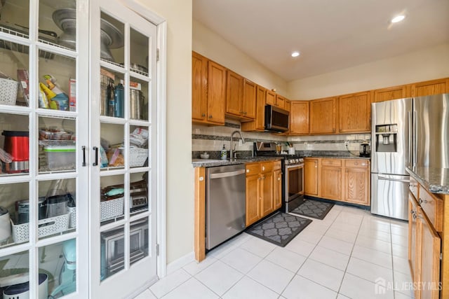1404 Yarrow Cir S, Brunswick, NJ 08810 - kitchen with appliances with stainless steel finishes, dark stone countertops, tasteful backsplash, light tile patterned floors, and brown cabinets