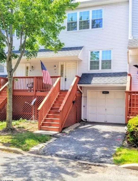 view of front of home featuring stairway, an attached garage, covered porch, and driveway