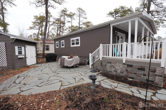 back of property featuring a patio and an outbuilding