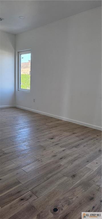 unfurnished room with dark wood-style flooring and baseboards