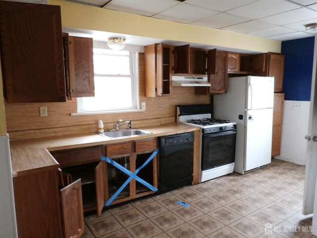 kitchen featuring gas range gas stove, a sink, light countertops, black dishwasher, and under cabinet range hood