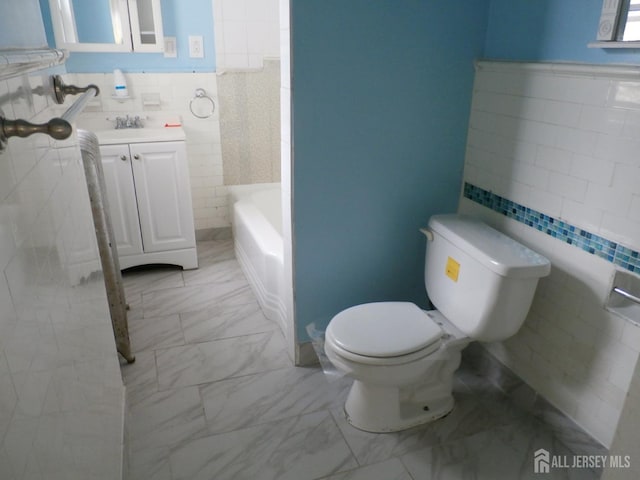 bathroom with a bath, tile walls, vanity, toilet, and marble finish floor