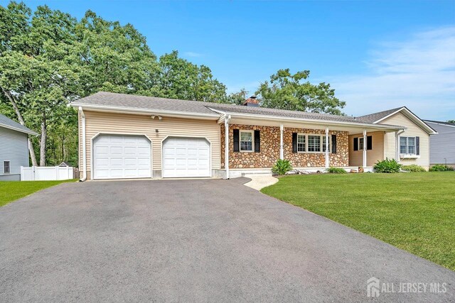 single story home featuring a front lawn, a porch, and a garage