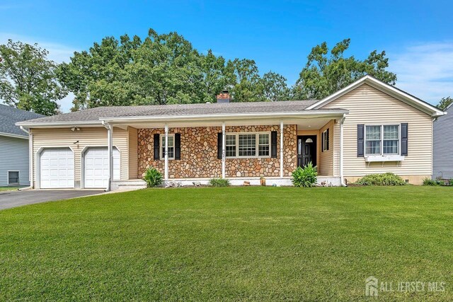 single story home with covered porch, a garage, and a front lawn