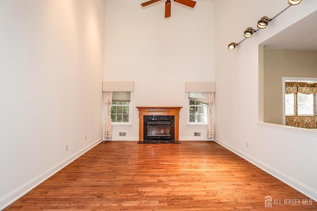 8 Staudt Ct, Franklin, NJ 08873 - unfurnished living room featuring plenty of natural light, a high ceiling, a ceiling fan, wood finished floors, and a fireplace