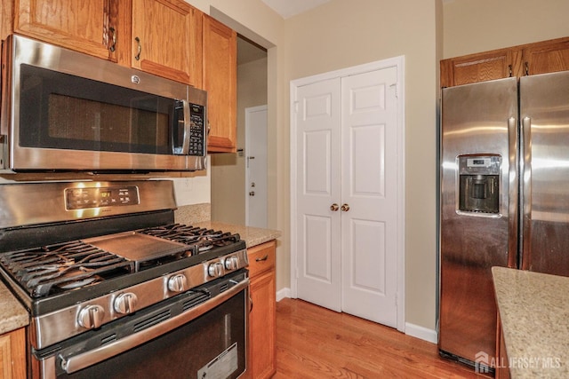 8 Staudt Ct, Franklin, NJ 08873 - kitchen with appliances with stainless steel finishes, light wood-style flooring, brown cabinetry, and light stone counters